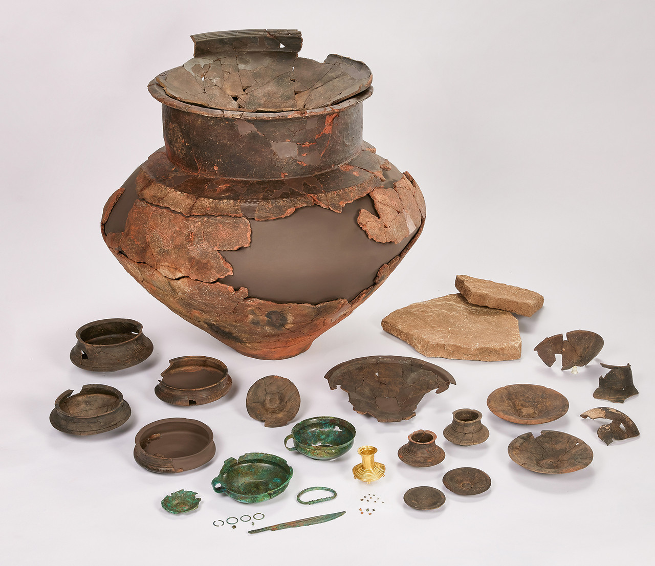 Bronze Age grave goods from Albisheim, Germany, including ceramic vessels, bronze objects, and a mysterious gold artifact dating back approximately 3,000 years.
