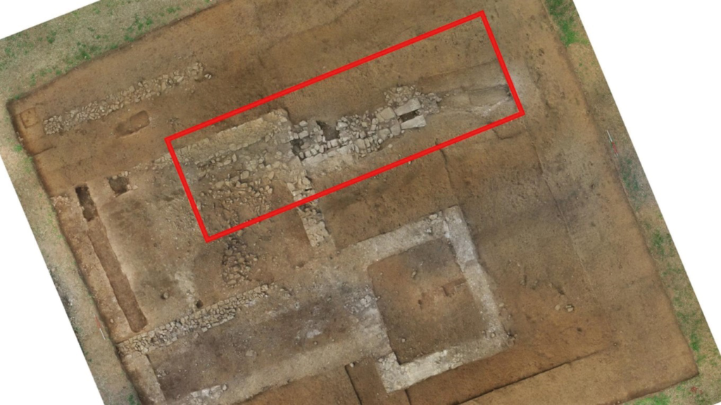 Aerial view of Trench 3 at the Rossett Roman villa in North Wales, with stone wall remains and the highlighted hypocaust flue and stoke area visible from above.