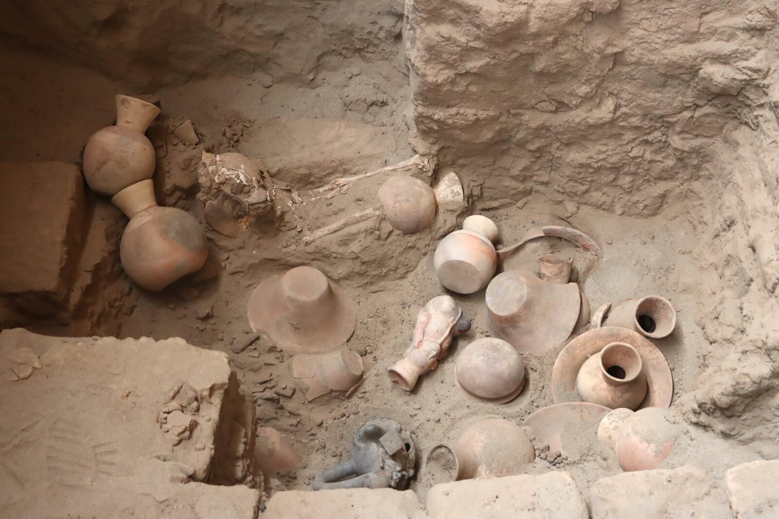 Archaeologists in Peru have uncovered an unusual Moche tomb containing 32 funerary offerings, among them ceramic figures of a bird-like deity and a prisoner with a rope around his neck.