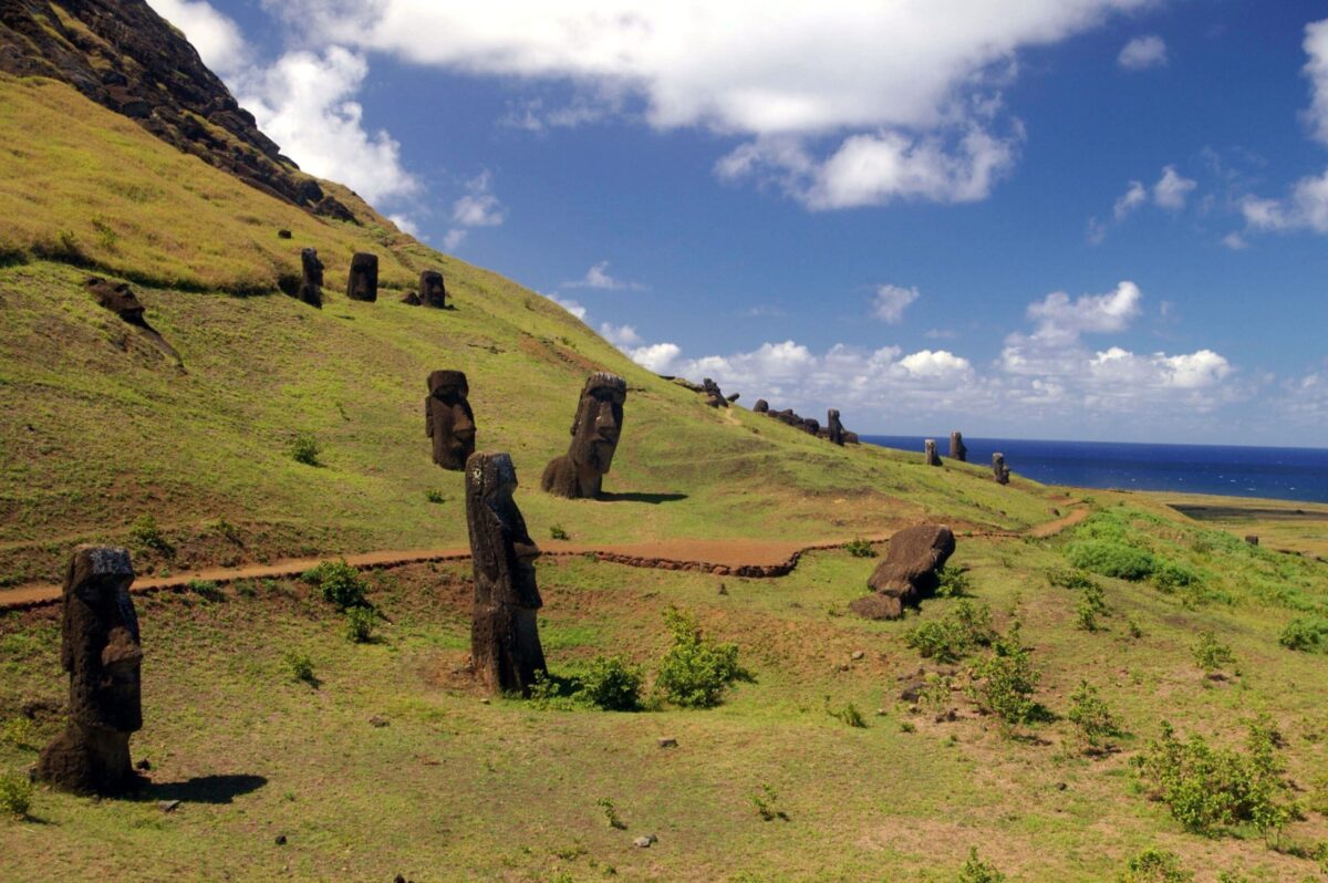 Moai statues stand on a grassy slope on Easter Island.
