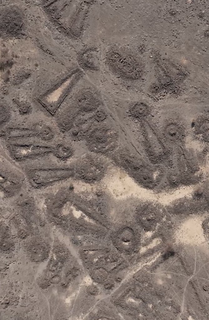 Aerial photograph showing ancient stone structures and geometric archaeological features across the desert landscape of northwestern Saudi Arabia.